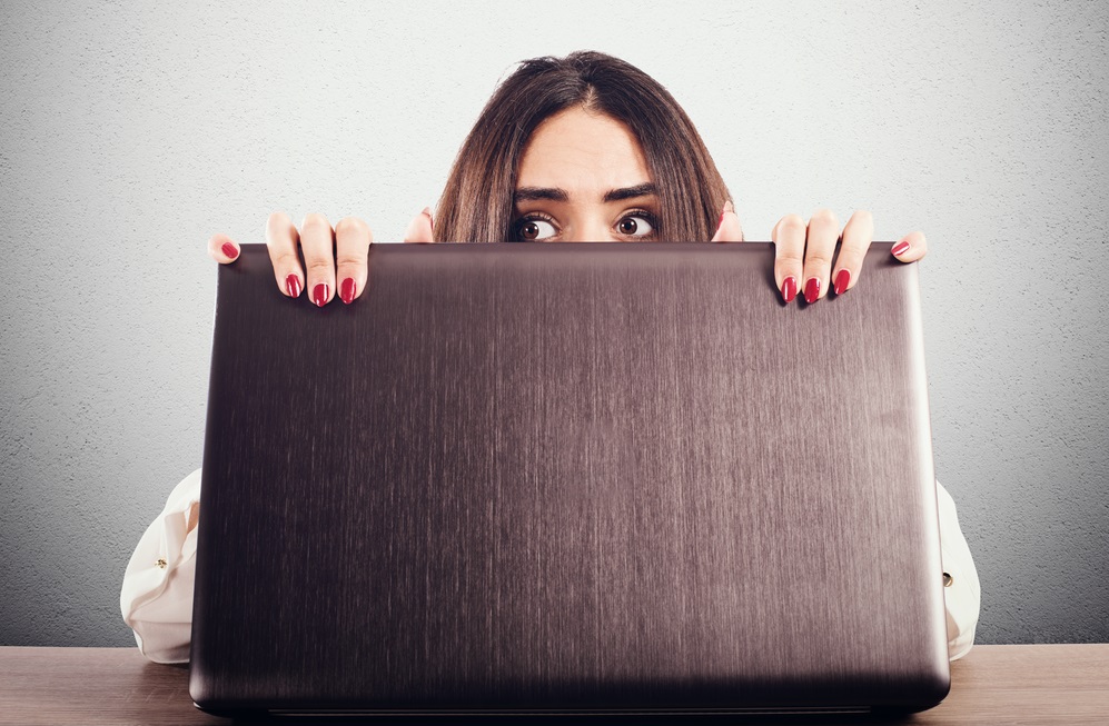 Woman hidden behind the computer screen peeks secretly
